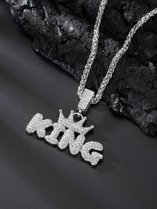 Close-up of silver King pendant necklace with sparkling stones on dark stone background