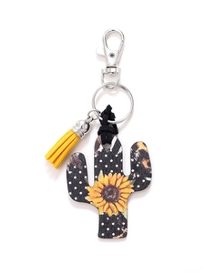 Macro detail of cactus wooden keychain with sunflower print and yellow tassel charm