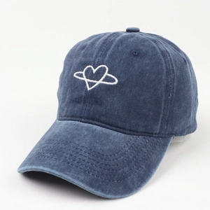 Detail of blue washed denim baseball cap with white heart planet embroidery and stitching
