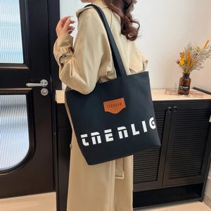 Large black canvas tote bag with THEALIG print and leather patch for daily commuting