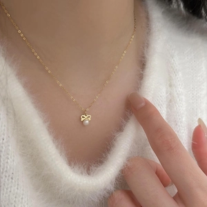 Close-up of elegant gold bow pendant with white pearl on model's neck for a chic look