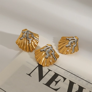 Schelp oorbellen in goud en zilver met witte parels op een modetijdschrift