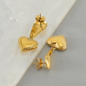Macro detail of golden stainless steel heart earring with radial embossed texture