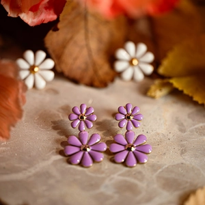 Close-up of purple daisy enamel earrings in stainless steel with golden center detail