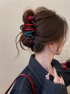 Detail of wavy colorful hair claw clip with red ball accent on model's hair