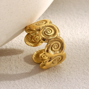 Macro detail of 18K gold plated seashell spiral ring on a white ceramic dish
