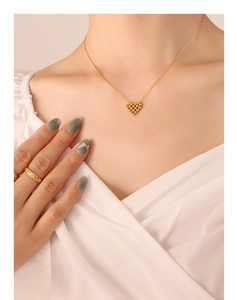 Detail of a gold-plated heart pendant necklace and textured ring on a female model