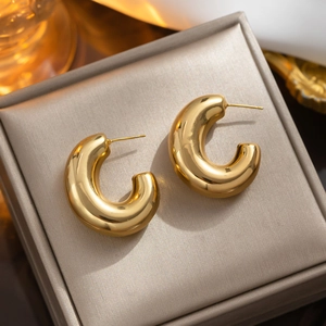Polished 18K gold stainless steel chunky C-shaped hoop earrings on beige velvet tray
