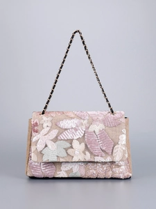 Detailed close-up of floral embroidery and sequins on a woven straw shoulder bag