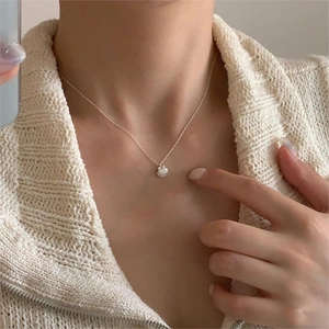 Detailed view of an S925 sterling silver shell pendant necklace on a woman's collarbone