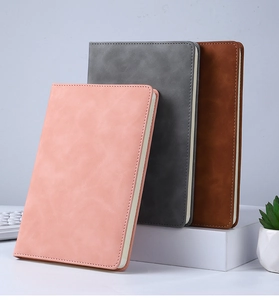 Detailed stack of pink, gray and brown PU leather A5 journals on a clean office desk
