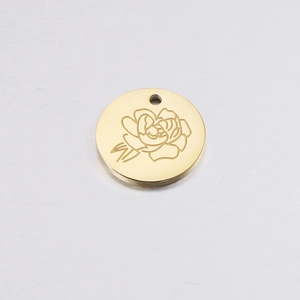 Close-up of golden round birthday flower pendant with engraved rose pattern and top hole