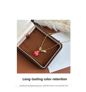 Close-up of 18k gold plated necklace with a detailed red apple pendant on velvet background