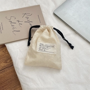 Close-up of cream canvas drawstring pouch with cotton ropes and minimalist fabric label