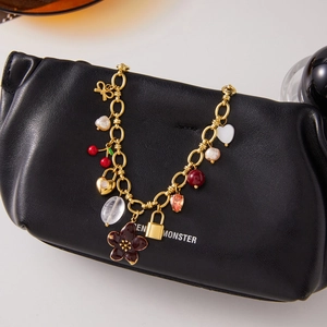 Luxurious gold stainless steel pearl necklace with flower, lock and heart charms on black bag