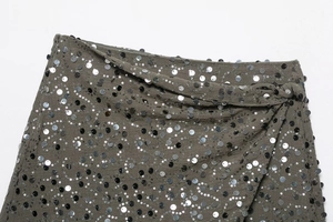 Dettaglio ravvicinato di paillettes verde scuro e vita con fiocco sulla gonna