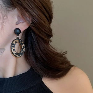 Gros plan d'une femme portant de grandes boucles d'oreilles ovales à imprimé léopard