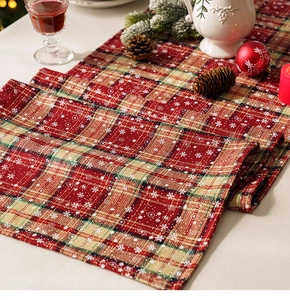 Close-up of linen textured plaid table runner with snowflakes in a festive Christmas setting