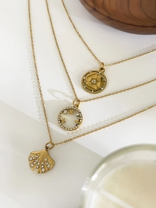 Detailed view of three layered gold necklaces featuring shell and star coin pendants
