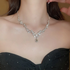 Close-up of a silver necklace with a teardrop pendant set with sparkling zircons on a model