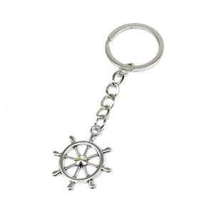 Close-up of a silver nautical ship wheel keychain with a polished metallic finish