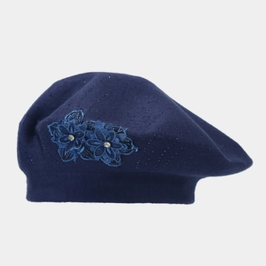 Detailed view of navy blue knitted beret with lace flower and sparkling rhinestone accents