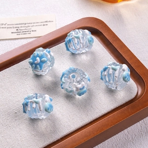 Close-up of five blue and white striped glass beads on a wooden jewelry tray for DIY crafts