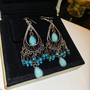 Macro shot of silver alloy teardrop earrings with blue gemstones and rhinestones