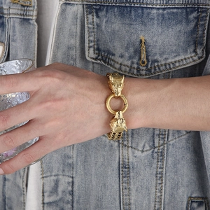 Detail of gold-plated wolf head bracelet with ring clasp on a male model's wrist