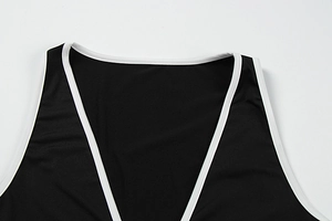 Détail du col en V profond avec liseré blanc contrasté sur un body de yoga noir