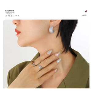 Detail of model wearing C-shaped crystal earrings and a gold ring with brown gemstone