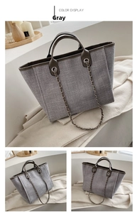 Detalle del bolso tote de lona gris con correa de cadena en un ambiente acogedor