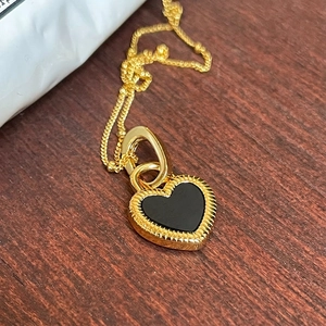 Elegant gold heart pendant necklace with black onyx inlay on a vintage wooden background