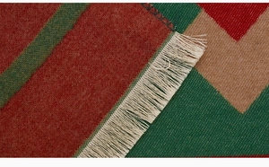 Detail of red and green geometric knit pattern with delicate white fringe tassels