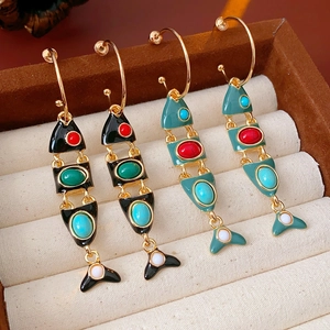 Detailed macro view of vintage fish-shaped enamel earrings with colorful gemstones
