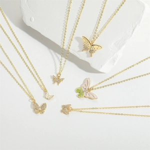 Elegant gold butterfly pendant necklaces set with zircon stones on white background