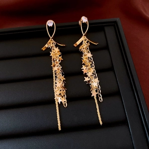 Macro detail of gold tassel star earrings with sparkling crystals on black display