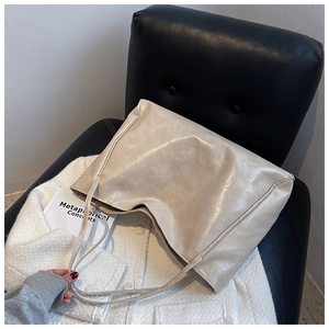 Detail of soft cream tote bag showing faux leather texture on a tweed coat