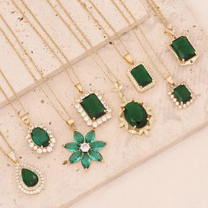 Detail of diverse emerald zircon pendants with gold plating on a textured stone surface
