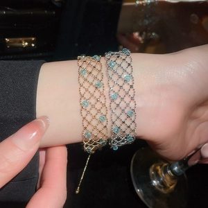 Close-up of gold and silver mesh bracelets with blue rose beads and adjustable slider clasp