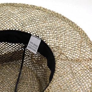 Flacher Strohhut mit breiter Krempe, Innenschweißband und Details aus natürlichem Grasmaterial