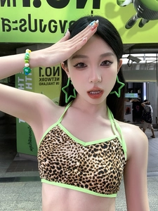 Close-up of vibrant green star earrings worn by a model with a leopard print bikini