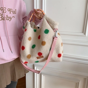 Detail of plush tote bag with colorful dots, woven orange handle and pink nylon strap