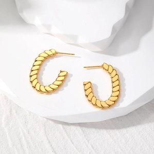 Detailed close-up of gold twisted rope C-shape hoop earrings on a minimalist white stand