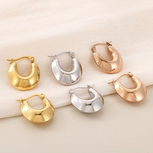 Three pairs of chunky U-shaped hoop earrings in gold, silver and rose gold on silk fabric