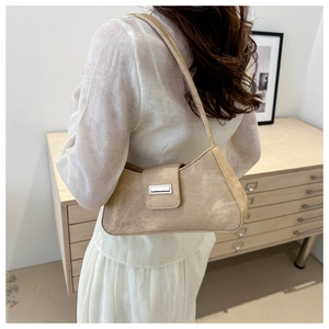 Close-up of beige suede shoulder bag with rectangular metal buckle on a model back