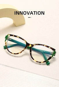 Detail of tortoise shell cat-eye glasses with green temples on a minimalist background