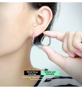 On-ear view of minimalist silver geometric hoop earrings in stainless steel on a model