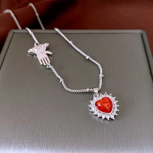 Detail of silver necklace with red heart pendant, white rhinestones, and palm charm