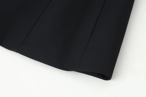 Detail of premium black woven blazer showing V-neck puff sleeve fabric texture and hem
